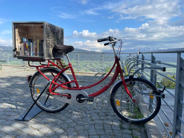 Fahrrad mit Bücherkiste auf dem Dorfplatz Sulzberg